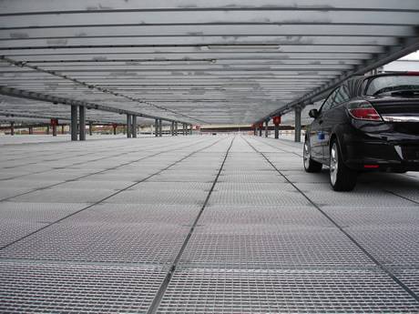 A car is passing through the steel grating floor of port parking.