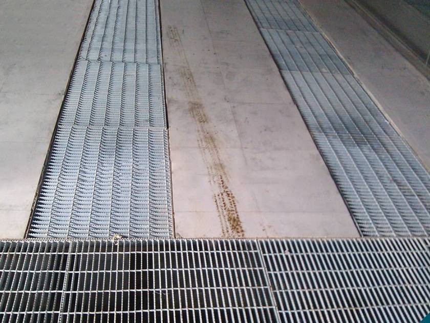 Several pieces of steel bar grating on the ground as the trench cover.