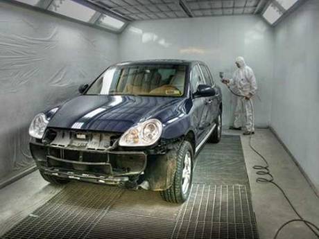 A worker is painting the car in painting workshop.