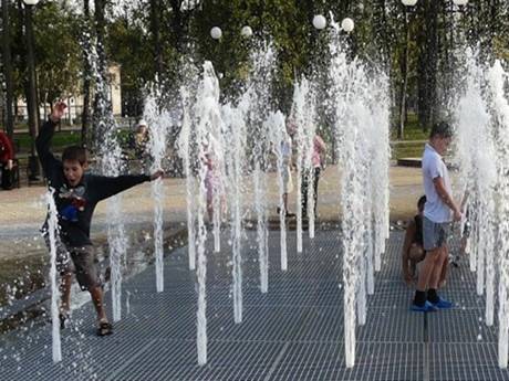 Plusieurs enfants rebondissent sur le drainage de la fontaine à râpes en acier.