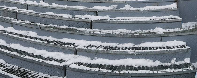 Welded bar grating stair tread for football field stair, and snow on it.