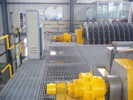 The ball mill is working in a corner of factory with steel grating floors.