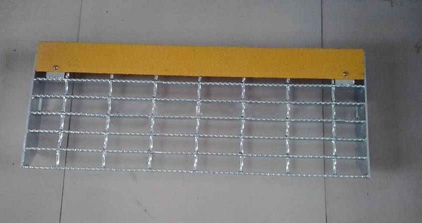 A galvanized serrated grating stair tread with twist cross bar and bolted with flat bar anti-slip plate on the floor.