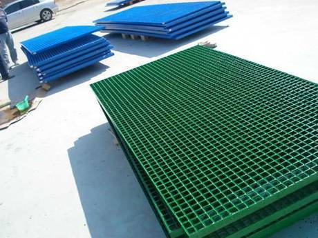 Some green and blue powder coated gratings placed on the ground.