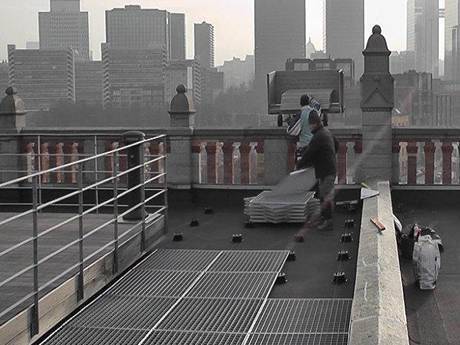 Deux ouvriers installent des planchers de caillebotis en acier sur le toit.