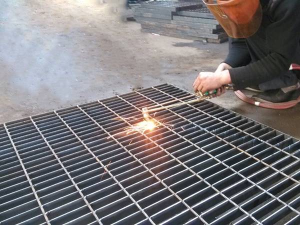 A welder is welding steel grating manually.