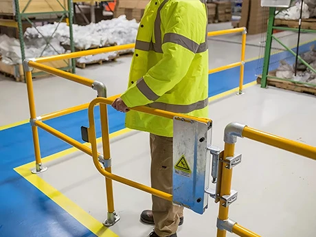 Le personnel ouvre la barrière de sécurité à fermeture automatique pour sortir du kit de main courante modulaire.