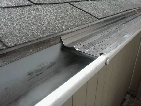 Perforated aluminum gutter guard is installed above the gutter system.