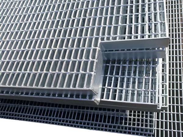 Two pieces of welded steel bar grating are cut a corner for pipes.