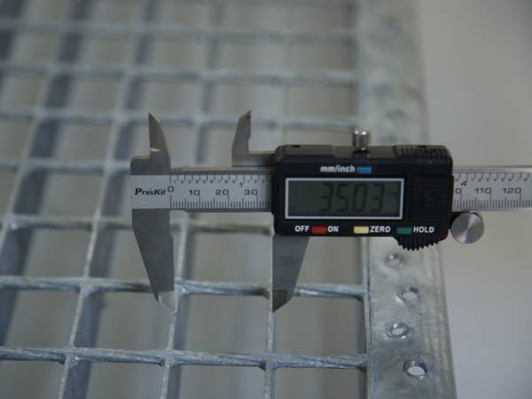 Un travailleur teste le diamètre de la barre de roulement de la grille de barre d'acier.