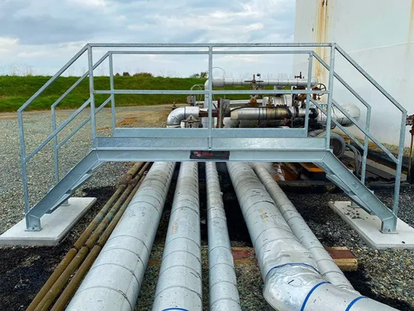 Caillebotis en acier pont piétonnier avec des escaliers et des mains courantes sur les pipelines.