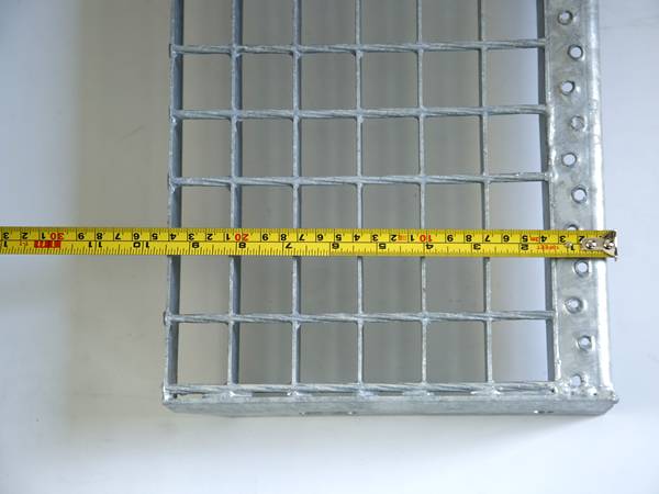 A worker is testing the width of steel grating